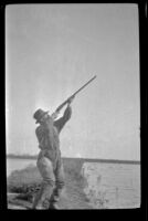 Frank Mellus aims his gun towards the sky, Seal Beach vicinity, 1916