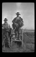 Frank Mellus and Keeper E. D. Hardy pose by the stile, Seal Beach vicinity, 1916