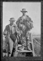 H. H. West and Keeper E. D. Hardy pose by the stile, Seal Beach vicinity, 1916