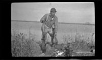 H. H. West stands by the blind with his rifle and ducks, Seal Beach vicinity, 1917
