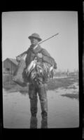 Beecher Laswell poses with his rifle and a string of ducks, Seal Beach vicinity, 1920