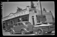 Car and trailer parked in front of a café and store, Toms Place, 1940