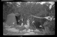 Mertie West stands under a tarp at a campsite at Rock Creek, Mammoth Lakes vicinity, 1940