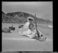 Elizabeth West, Mary A. West and Frances West sit on the beach with a rifle, Topanga vicinity, about 1907
