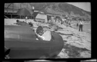 H. H. West, Jr. sits in a canvas canoe at the beach, Topanga, about 1922