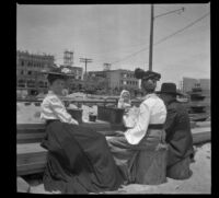 Mary West sits on a wooden bench eating lunch with her daughter, Elizabeth West, and her in-laws, George and Wilhelmina West, Venice, about 1903