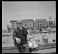 H. H. West sits on a pile of wooden planks with his daughter, Elizabeth, Venice, about 1903