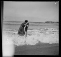 Mary West holds her daughter, Elizabeth while standing in the surf, Venice, about 1903
