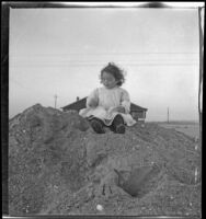 Elizabeth West sits on a pile of sand, Venice, about 1905