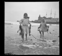Elizabeth and Frances West stand in the surf holding kelp, Venice, about 1910