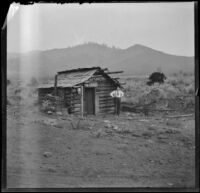 George M. West poses next to a log cabin, Yreka, 1898