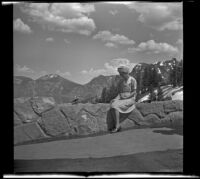 Mertie West feeds a bird and a chipmunk while sitting on a parapet overlooking Crater Lake, Crater Lake National Park, 1942