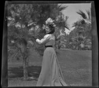 Daisy Kellum holds the branch of a tree in MacArthur (Westlake) Park, Los Angeles, about 1898