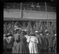 Crowd at Southern Pacific Railroad's River Station watch soldiers eating behind palm leaves, Los Angeles, 1898