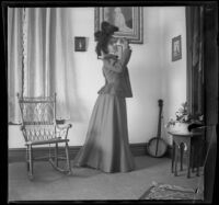 Daisy Kellum poses while holding a flower in her home, Los Angeles, about 1899