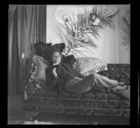 Minnie Kellum dons men's attire and lounges on a sofa in her family's home, Los Angeles, about 1899