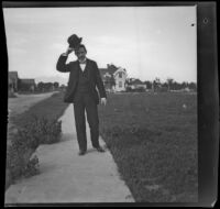 H. H. West walks down a sidewalk and tips his hat, Los Angeles, about 1899