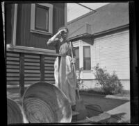 Mary West stands on the West's back porch holding a broom, Los Angeles, about 1899