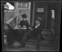 Wayne W. West, Nella A. West and Charles Rucher sit on the front porch steps of the West's residence, Los Angeles, about 1900