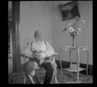 George M. West sits on a rocking chair in the West's parlor, Los Angeles, 1899