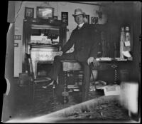 H. H. West leans on the table in the library of the West's house, Los Angeles, 1899