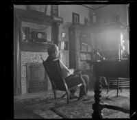 George M. West sits on a rocking chair in the library of the West's house, Los Angeles, about 1898