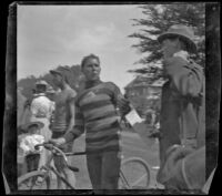 Guy West holds his bike while speaking to another man, Los Angeles, about 1900