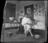 H. H. West sits on his sister's bed holding a doll, Los Angeles, about 1900