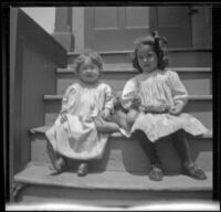 Frances and Elizabeth West sit on the back steps of a house with a teddy bear between them, Los Angeles, about 1907