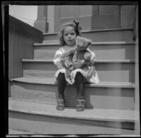 Elizabeth West sits on the back steps of a house holding teddy bear, Los Angeles, about 1907