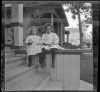 Frances and Elizabeth West sit on the side of front porch steps, Los Angeles, about 1907