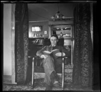 Wilfrid Cline sits on a chair reading a book in the West's house at 139 South Daly Street, Los Angeles, about 1903