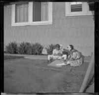 Frances and Elizabeth West sit behind the West's house playing jacks, Los Angeles, about 1912