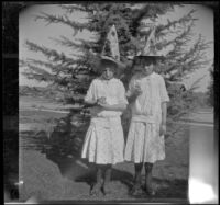 Frances and Elizabeth stand on the West's front lawn wearing witch hats, Los Angeles, about 1914