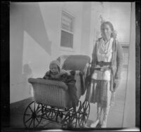 Elizabeth West stands next to her baby brother, H. H. West Jr., who is in a stroller, Los Angeles, about 1918