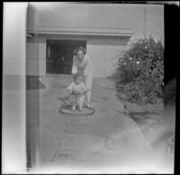 Elizabeth West helps her brother, H. H. West Jr., who is in a baby walker, Los Angeles, about 1919