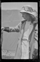Elizabeth West stands in the West's backyard holding a fish, Los Angeles, about 1919
