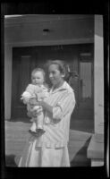 Elizabeth West holds her baby brother, H. H. West Jr., while standing in front of the West's house at 1644 Wellington Road, Los Angeles, about 1917