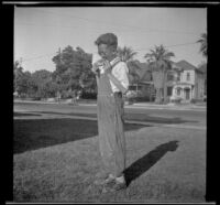 H. H. West Jr. stands on the front lawn of 2223 Griffin Avenue eating watermelon, Los Angeles, about 1930