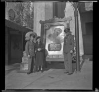 Gilbert Cecil West, Mertie West, and William Roscoe Wright stand next to a movie poster in front of Grauman's Chinese Theatre, Los Angeles, 1941