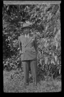 H. H. West stands in front of a wisteria plant in his backyard, Los Angeles, 1942