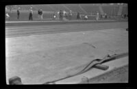 View of the track and people preparing for a track event at the Olympic Games, Los Angeles, 1932