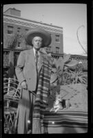 Dr. Bim Smith stands in his backyard wearing a serape and a hat, Los Angeles, 1939