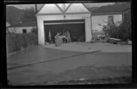 Freshly poured cement dries in the Siemsen's yard while Elizabeth Siemsen and workmen lunch in the garage, Glendale, 1943