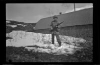 H. H. West, Jr. poses with a rifle outside his quarters, Dutch Harbor, 1943