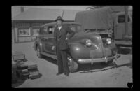 H. H. West poses in front of a car outside the Southern Pacific Railroad depot (negative), San Luis Obispo, 1942