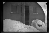 Exterior of H. H. West, Jr.'s quarters at Fort Mears, lined by piles of snow, Dutch Harbor, 1942 or 1943