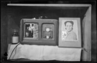 H. H. West, Jr.'s radio and pictures of his wife, Anna West, and Elizabeth and Al Siemsen sit on a shelf in his quarters, Aleutian Islands, 1943