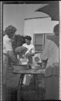 Alice Shaw washes a salad bowl in the rear yard of W. H. Shaw's home, Los Angeles, 1945