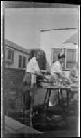 Alice Shaw and others wash dishes in the rear yard of W. H. Shaw's home, Los Angeles, 1945